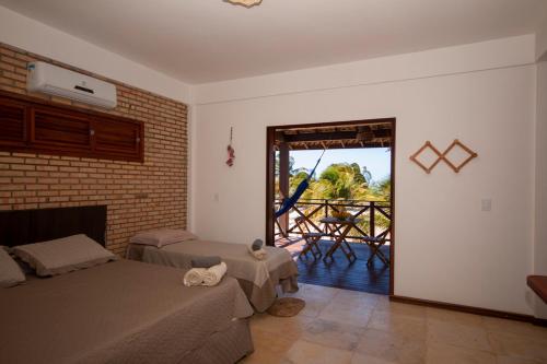a bedroom with two beds and a balcony with a table at BEACH HOUSE - Apartment 2 - com cozinha - with kitchen in Barra Grande