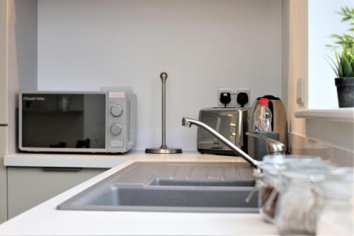 a kitchen with a sink and a microwave at The Coach House - Free Private Parking - by Property Promise in Cardiff