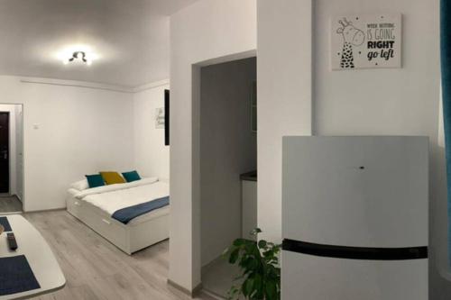 a white bedroom with a bed and a table at Cozy Studio Apartament Zalau in Zalău