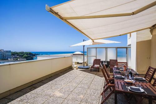 Un patio con mesas y sillas y vista al mar. en CLEO KEYWEEK Apartment with terrace sea views swimming pool, en Biarritz
