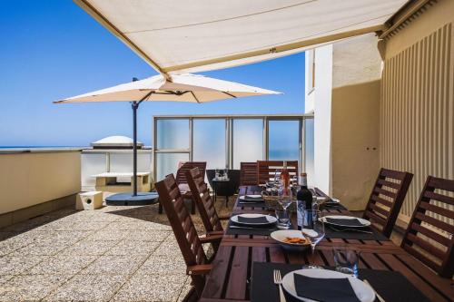 un patio avec tables, chaises et un parasol dans l'établissement CLEO KEYWEEK Apartment with terrace sea views swimming pool, à Biarritz