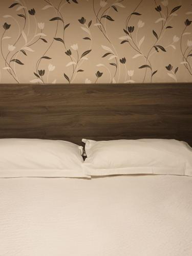 a bed with a wooden headboard with a flowery wallpaper at Logis Doubs Rivage in Charette