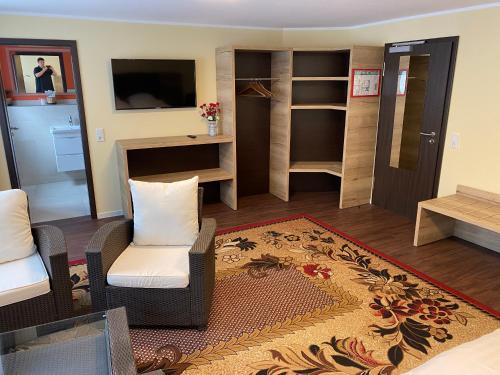 een woonkamer met een bank en stoelen en een televisie bij WIRTSHAUS am Niederntor in Blomberg