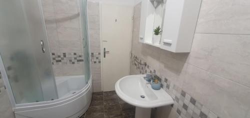 een witte badkamer met een wastafel en een douche bij Apartmani Matea in Trogir