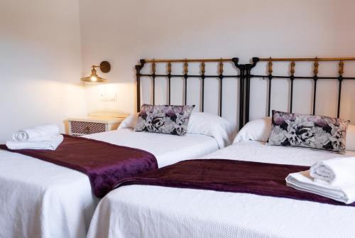two beds sitting next to each other in a room at Casa Rural Pozo Roñañuela in El Royo