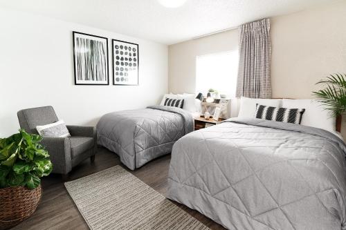 a bedroom with two beds and a chair at Intown Suites Extended Stay West Palm Beach FL - Military Trail Rd in West Palm Beach