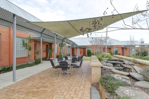 a patio with a table and chairs under an umbrella at Strath Motel in Strathalbyn