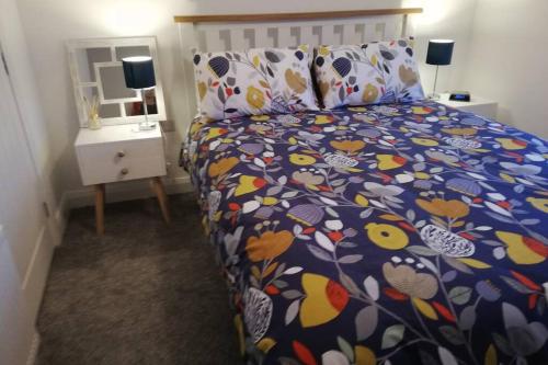 a bedroom with a bed with a colorful comforter at Mews Apartment, Bushmills in Bushmills