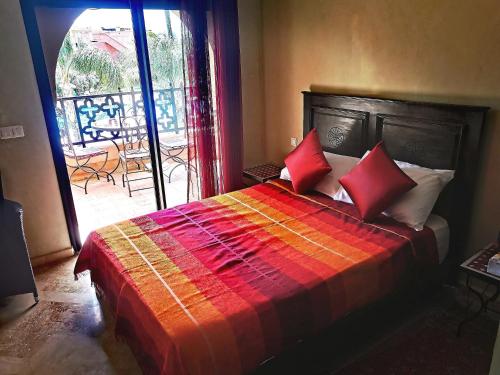 La Perle de l'Atlas by Golf Resort في مراكش: غرفة نوم بسرير ومخدات حمراء وشرفة