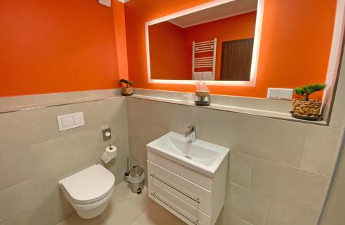 an orange bathroom with a toilet and a sink at WIRTSHAUS am Niederntor in Blomberg