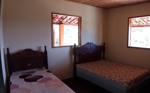 two beds in a small room with two windows at Casa grande, bem espaçosa, em Itambe do Mato Dentro, Cabeça de Boi in Itambé do Mato Dentro
