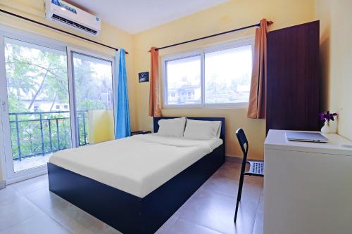 a bedroom with a bed and a desk with a laptop at Mariners Bay Suites in Calangute