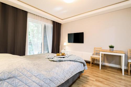een slaapkamer met een bed met een tafel en een televisie bij Apartament Izabella in Świnoujście