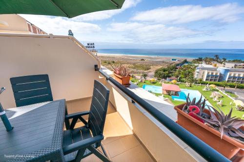 a balcony with two chairs and a view of the beach at Residence Palm Garden Ocean View in Morro del Jable