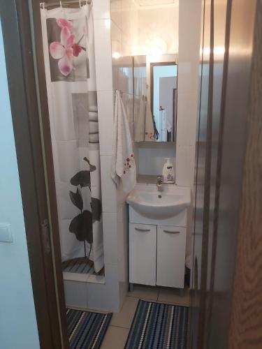 a white bathroom with a sink and a mirror at Apartament Nemira in Slănic-Moldova