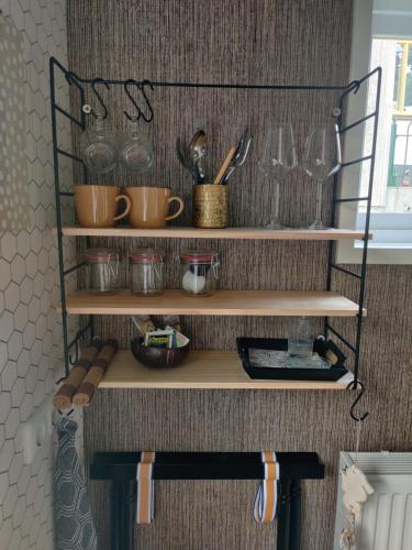 un estante con tazas y utensilios. en Thuis bij Elles, en Zuilichem