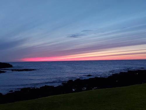 ポーツチュワートにあるAyalaの手前の岩を背景とした海上の夕日