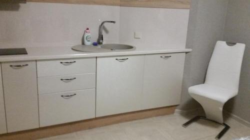 a bathroom with a sink and a white chair at Baltā in Ventspils