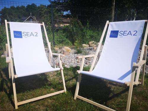 two lawn chairs sitting in the grass with signs at Sea2 in Nowęcin
