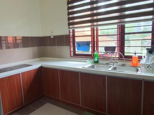 cocina con armarios de madera, fregadero y ventana en PH Homestay Bungalow House at PJ Fully Equipped en Petaling Jaya