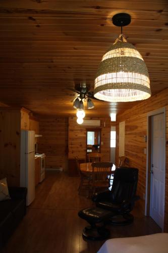 a living room with a chandelier and a table and chairs at Chalets et Spa Lac Saint-Jean in Chambord