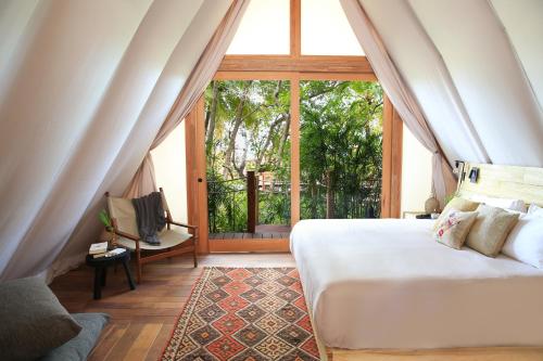 a bedroom with a bed and a large window at Our Habitas Bacalar in Bacalar