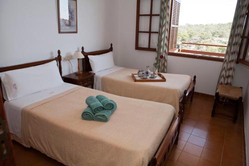 a hotel room with two beds with towels on them at Apartamentos Llevant in Cala Figuera