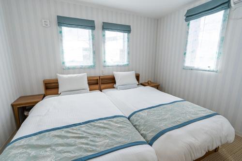 a bedroom with a large bed with two windows at Ecot Irabu Bridge Sunset Hills in Miyako Island