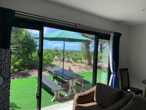a patio with a table and a bench and an umbrella at The Peridot Smart Hotel Tancha Ward in Onna