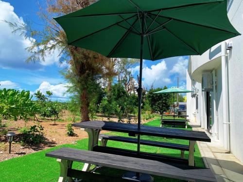 a picnic table with a green umbrella on a patio at The Peridot Smart Hotel Tancha Ward in Onna