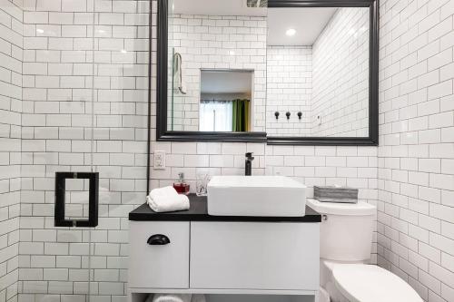 La salle de bains blanche est pourvue d'un lavabo et de toilettes. dans l'établissement Le Coureur Des Bois, à Québec