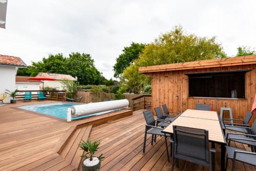 a wooden deck with a pool and a swimming pool at Frenchyhomes☆villadeluxe☆Plage☆piscine in Andernos-les-Bains