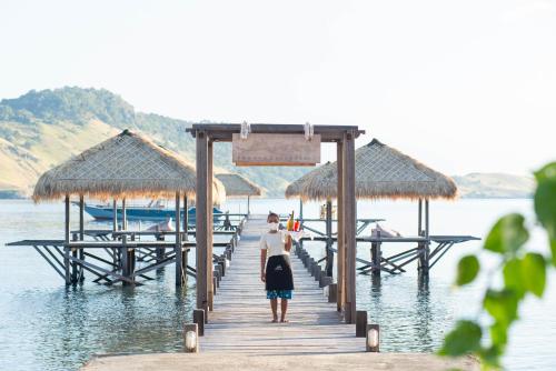 una mujer parada en un muelle en el agua en The Seraya Resort Komodo, en Labuan Bajo