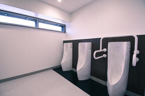 a bathroom with three urinals and a window at GATEWAY MAIZURU in Maizuru