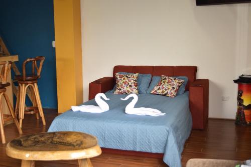 two swans sitting on a bed in a room at Casa Córa in Heredia