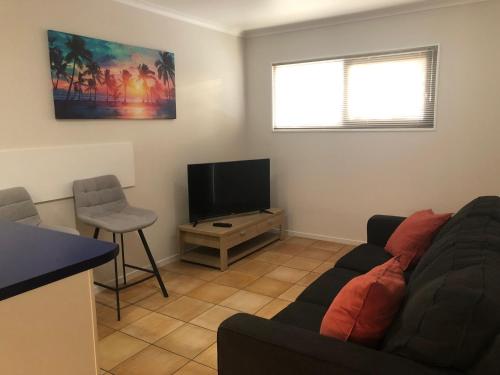 a living room with a couch and a flat screen tv at Cottage Park Thermal Motel in Tauranga