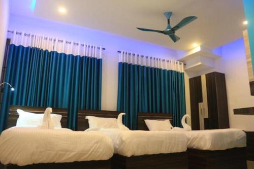 two beds in a room with blue and green curtains at Railview Residency in Alleppey
