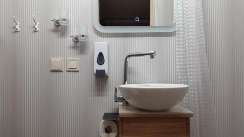 a bathroom with a sink and a tv on the wall at Baltā Studio with Patio & Free Parking in Ventspils