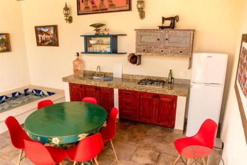a kitchen with a table and red chairs and a refrigerator at Casa Palmas by Majikal B&B in Mérida
