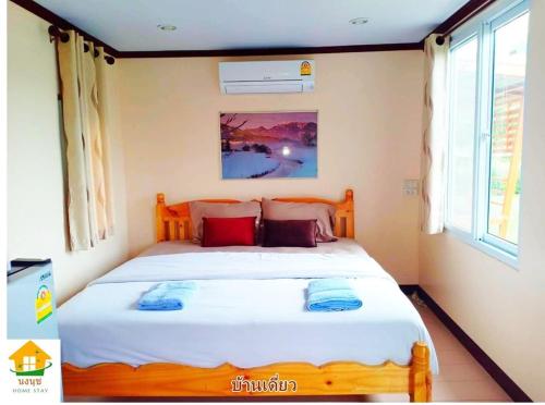 um quarto com uma grande cama branca com almofadas vermelhas em นงนุช โฮมสเตย์ & รีสอร์ท บุรีรัมย์ em Buriram