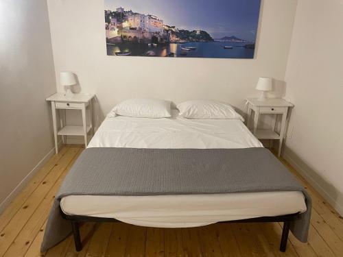 a bed in a room with two nightstands and a painting at Monaciello in Naples