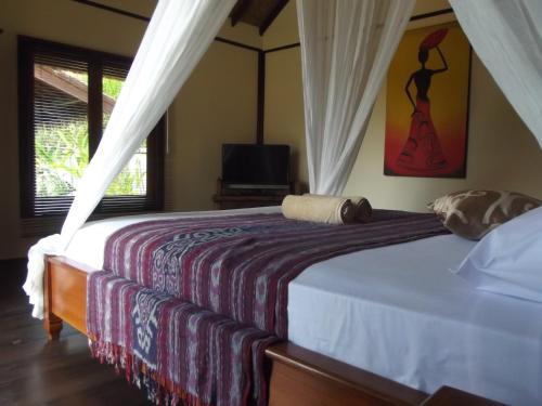 a bedroom with a bed and a television in it at Gili Flush Harmony in Gili Trawangan