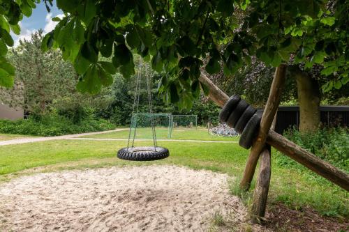 a tire swing hanging from a tree in a park at Stayokay Hostel Egmond in Egmond-Binnen