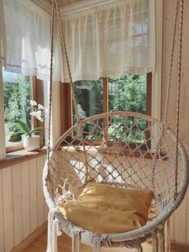 a swinging chair in a room with a window at Hellamaa Retrovisiit Alma & Vilma in Hellamaa