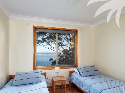 two beds in a room with a window at Sandbar View in Smiths Lake