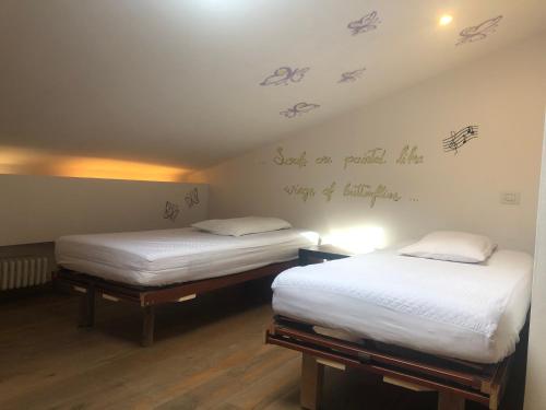 2 łóżka pojedyncze w pokoju z napisem na ścianie w obiekcie Appartamento mansardato w mieście San Giorgio Di Mantova