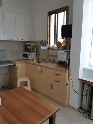 a kitchen with white cabinets and a wooden table at Квартира в непосредственной близости от моря и пляжа в Хайфе /Apartment near the sea and the beach in Haifa in Haifa