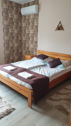 a large bed in a bedroom with a brick wall at Kövirózsa Vendégház in Szilvásvárad