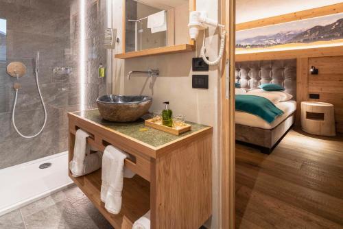 a bathroom with a sink and a shower and a bed at Garni Mia Co in Antermoia