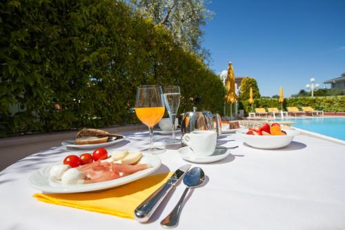 a table with a plate of food and a glass of wine at Hotel GARDENIA & Villa CHARME Adults Friendly 4Star service in Bardolino